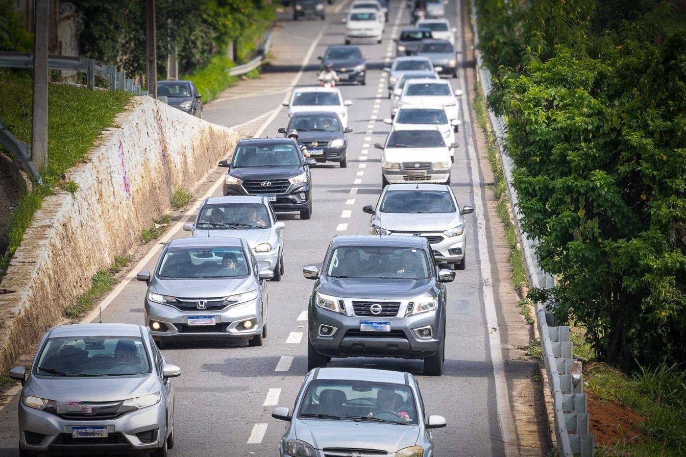 Fluxo de carros, caminhonetes e motocicletas em avenida de pista dupla, ilustrando o comércio de veículos em Goiás