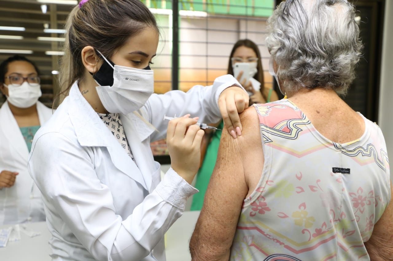 Profissional de enfermagem aplica vacina no braço de uma paciente idosa em unidade de saúde de Goiânia
