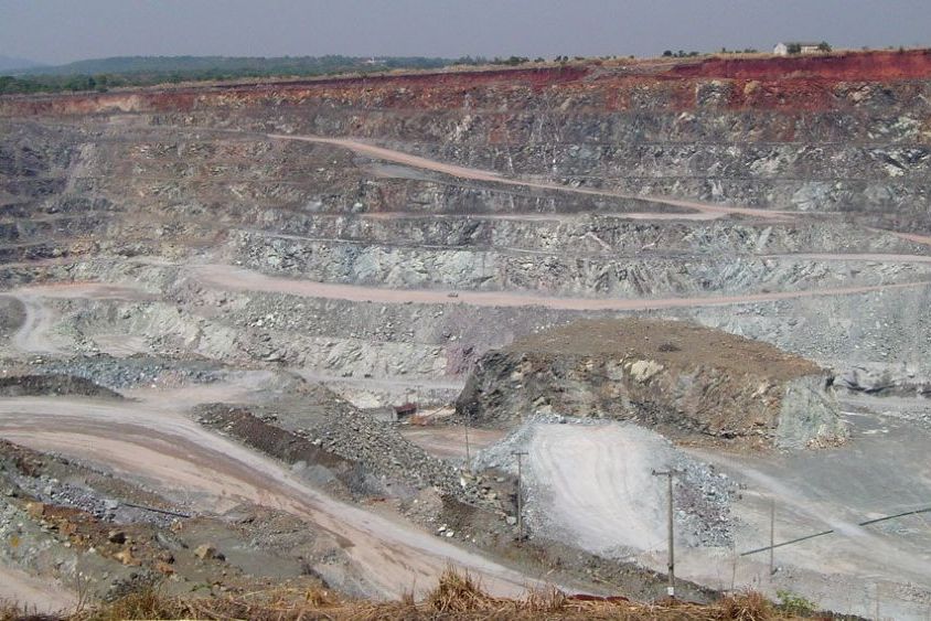 Cava a céu aberto de mineração de amianto crisotila, com bancadas de rocha acinzentada e estradas de acesso