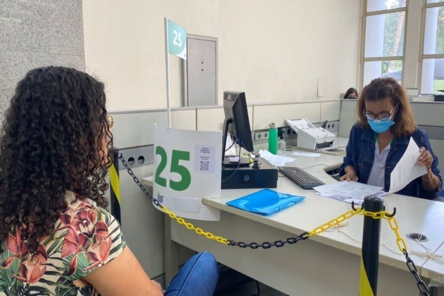 Atendente e cidadã conversam em guichê de atendimento de centro de conciliação