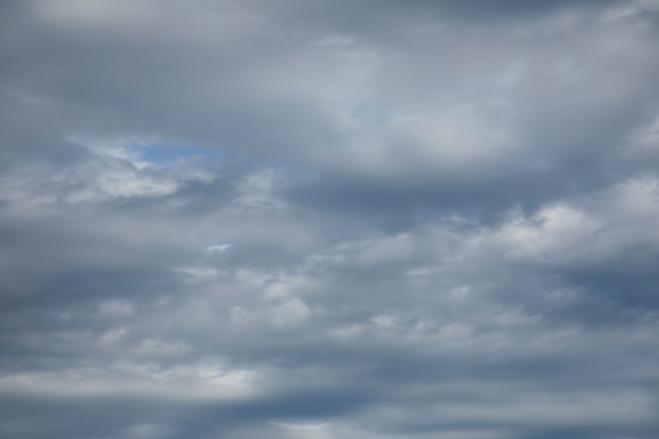 Céu encoberto por nuvens carregadas, com pequena abertura de céu azul à esquerda