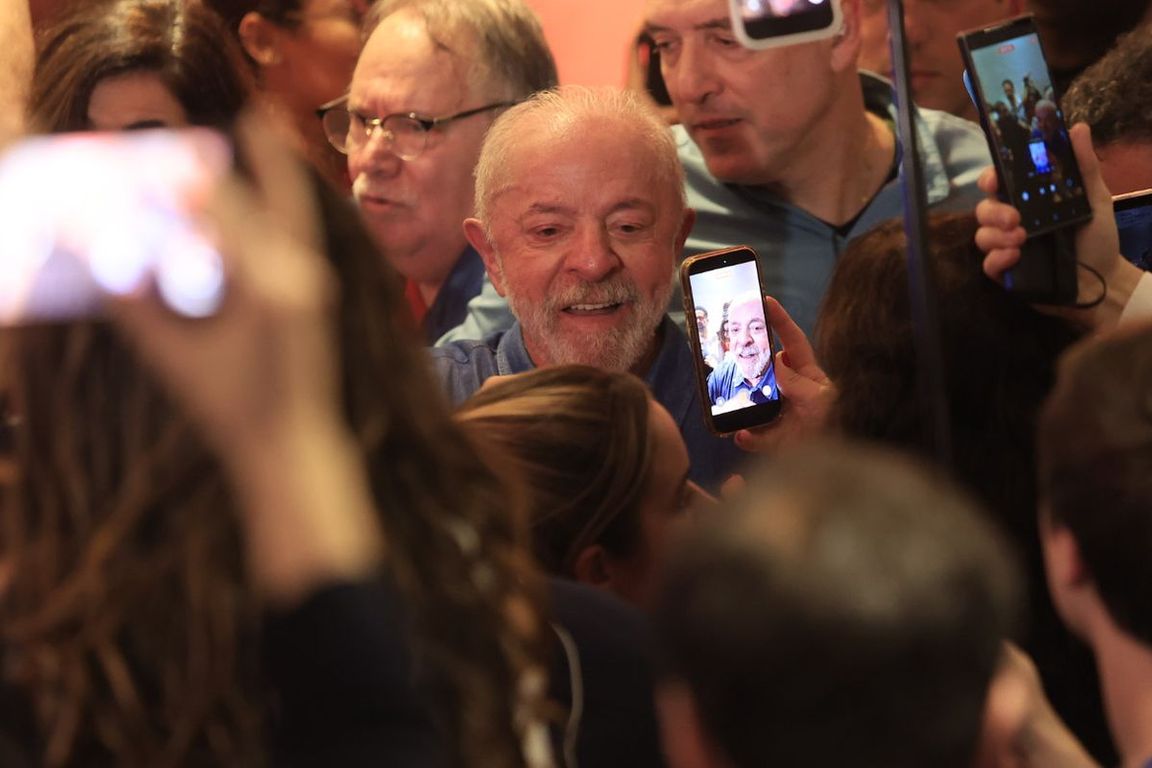 Presidente Lula cercado por apoiadores que o filmam com celulares na noite da vitória