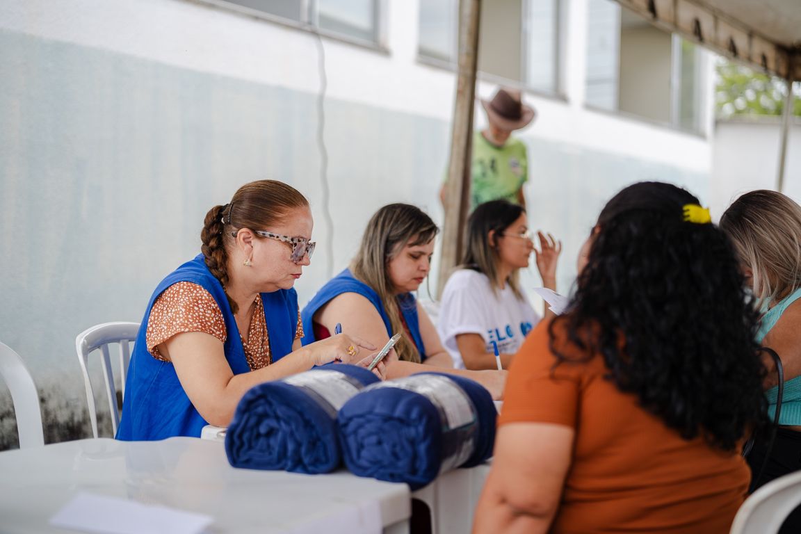 Servidoras de colete azul atendem moradores em mesa de ação social em Anápolis