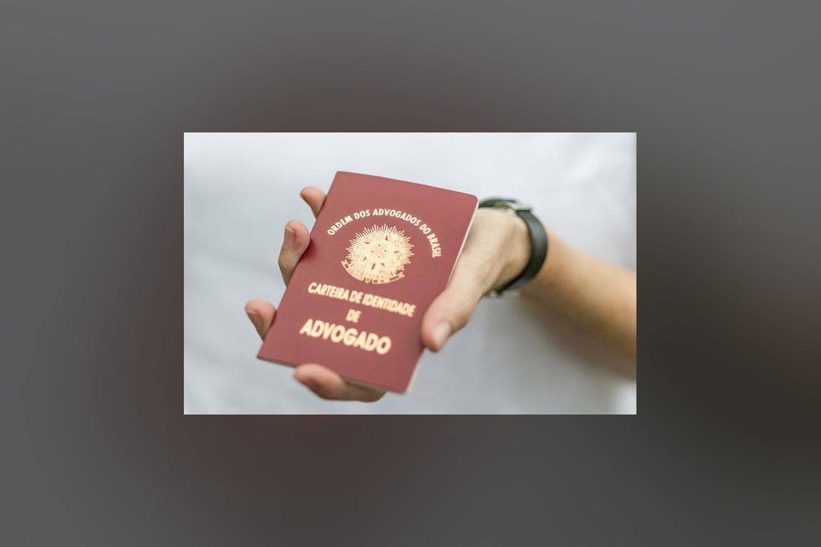 Mão segura carteira de identidade de advogado da OAB