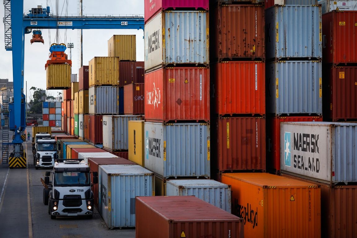 Caminhões e contêineres empilhados em terminal de carga para exportação