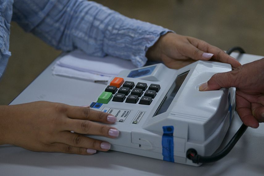 Mãos de eleitora digitando o voto em urna eletrônica