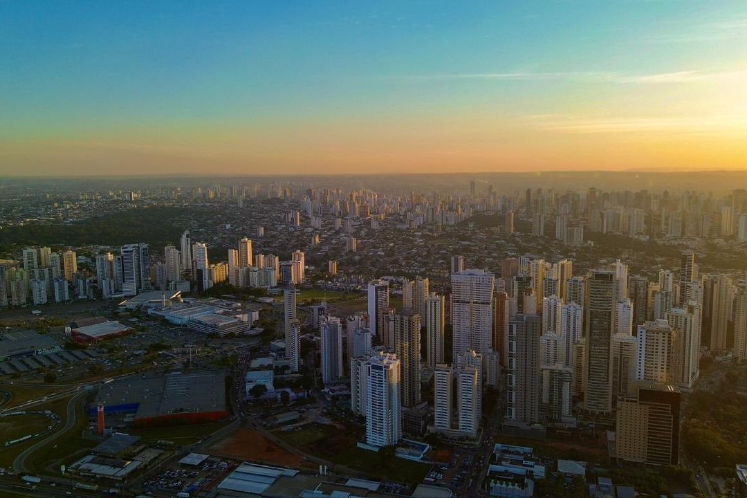 Vista aérea de Goiânia ao entardecer, com prédios residenciais e áreas verdes
