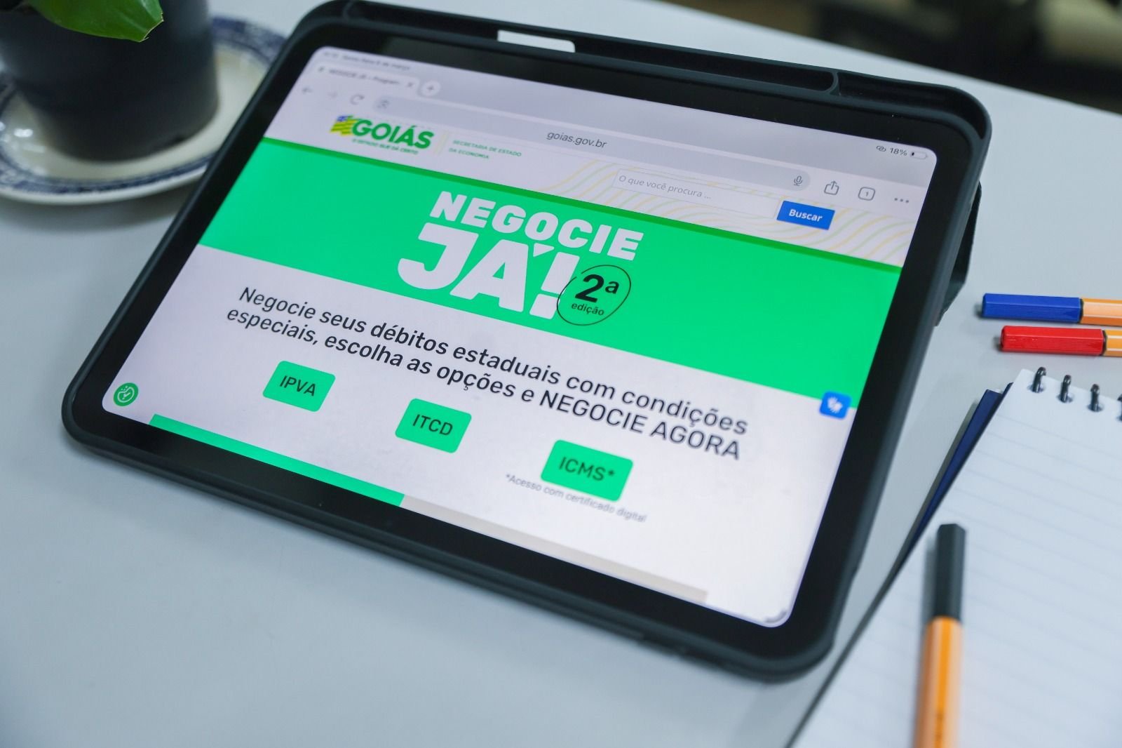 Tablet exibe a página do programa Negocie Já II, do Governo de Goiás, com as opções IPVA, ITCD e ICMS