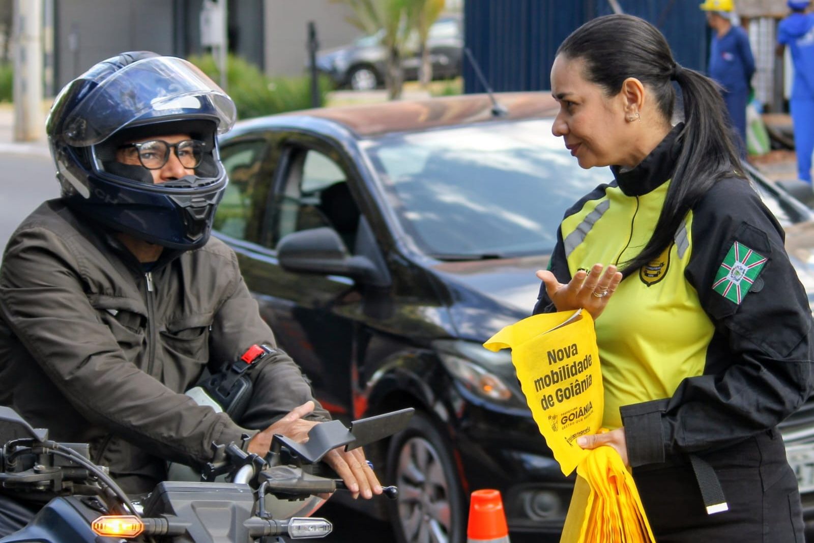 Agente de trânsito entrega material educativo a motociclista em blitz em Goiânia