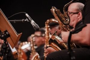 Músico toca saxofone ao lado de uma partitura em apresentação de banda sinfônica
