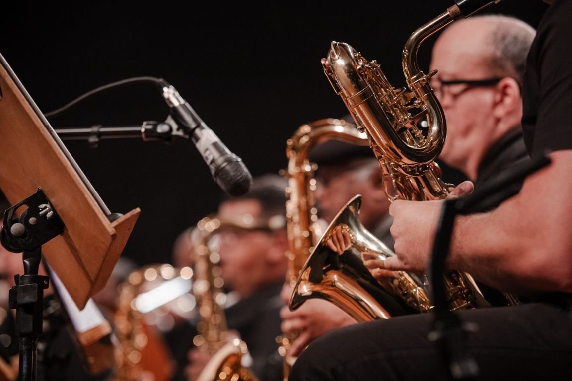 Músico toca saxofone ao lado de uma partitura em apresentação de banda sinfônica
