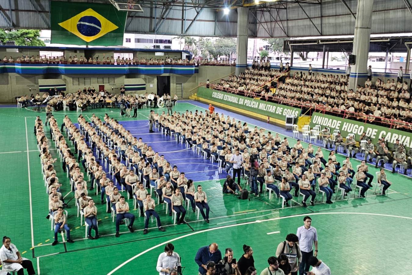 Alunos fardados sentados em quadra coberta de Colégio Estadual da Polícia Militar de Goiás
